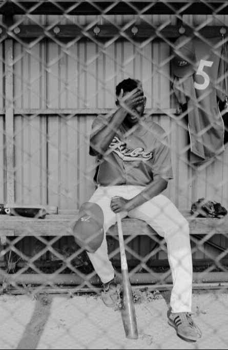 Baseball player sitting alone in the dugout, representing the hidden mental health struggles athletes can face.